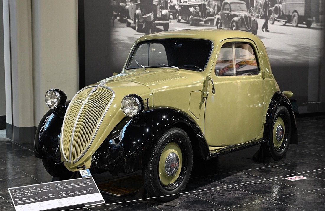Fiat 500 «Topolino» del 1936, piccola vettura color crema e nero, esposta in un museo dell'automobile