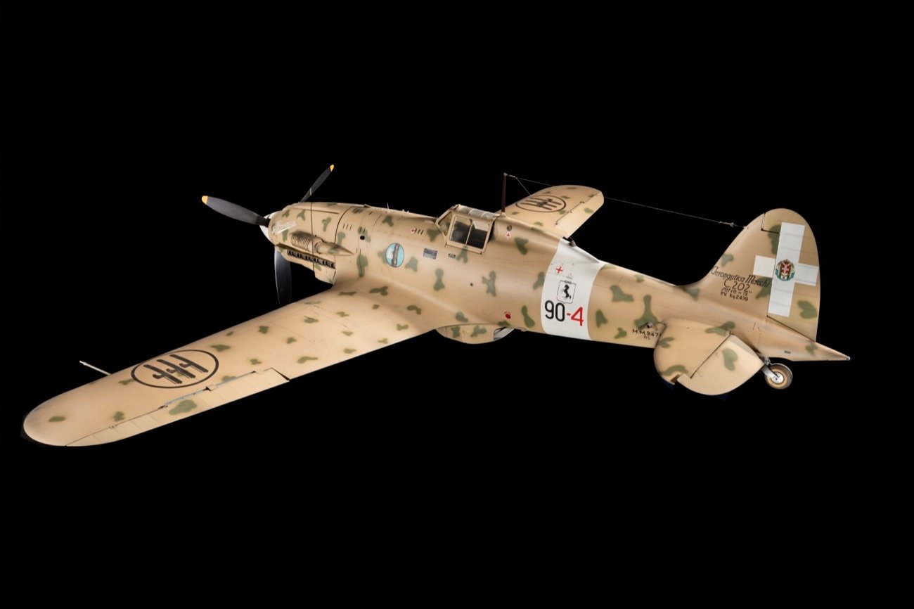 Caccia Macchi C.202 Folgore in livrea mimetica del deserto, vista di tre quarti su fondo nero